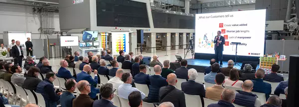 Auf dem Bild sieht man viele Personen und einen Sprecher